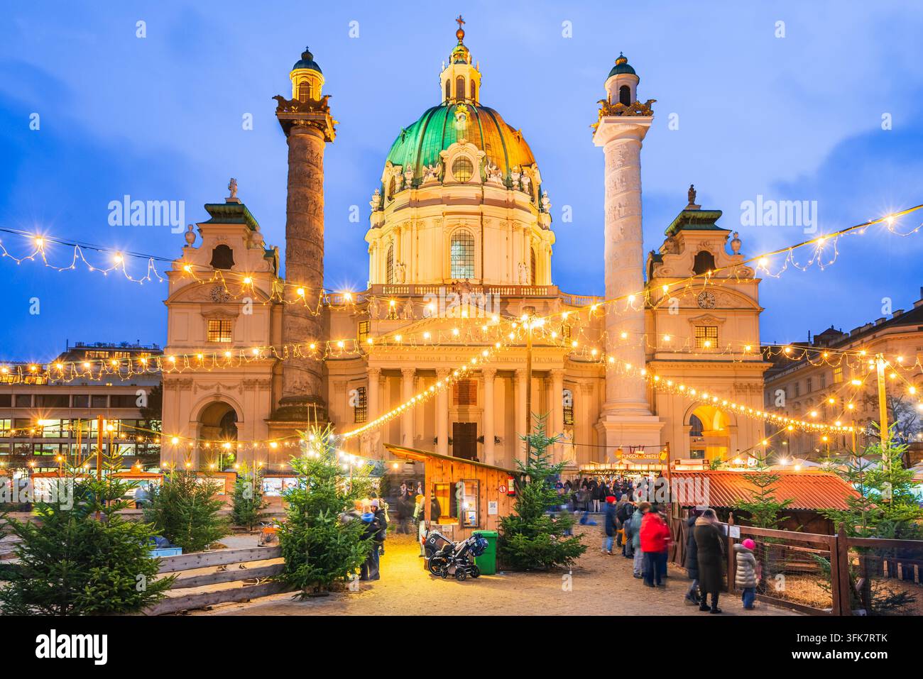 Wien, Österreich - 17. Dezember 2025. Menschenmenge besucht den beleuchteten Weihnachtsmarkt am Karlsplatz zur Blauen Stunde Stockfoto
