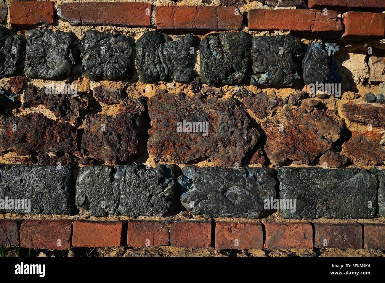 Historische Wandtextur aus dunklen Schlackenblöcken und roten Ziegeln Stockfoto
