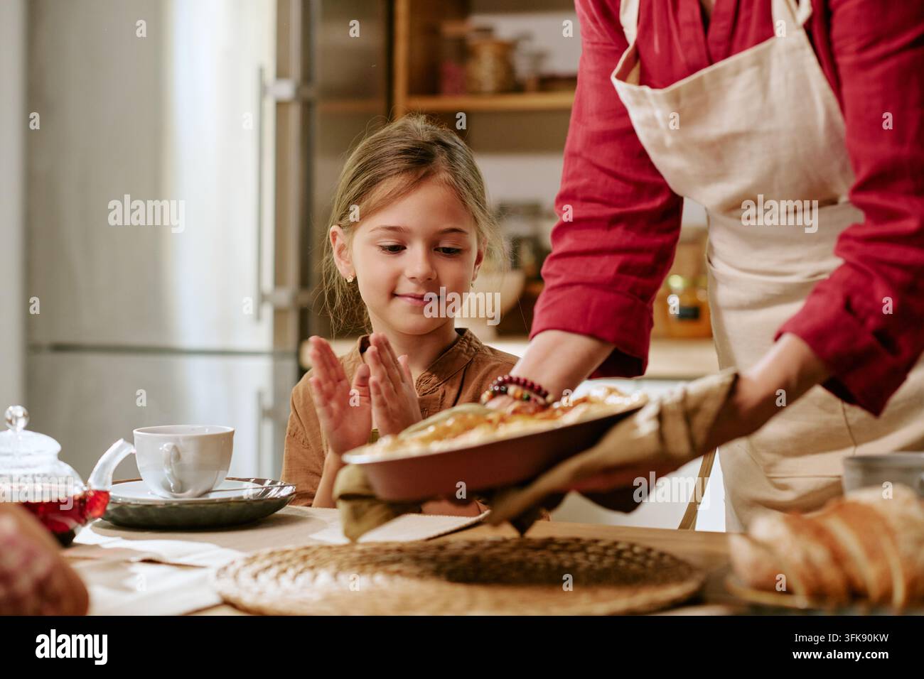 Seniorin serviert frisch gebackenen Kuchen an ein glückliches Mädchen zu Hause Stockfoto
