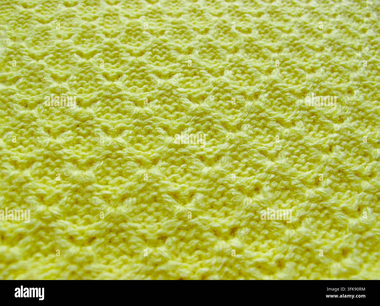 Gelbe gestrickte Stofftextur mit diamantförmigem geometrischem Muster, Nahaufnahme für Textilhintergrund, handgefertigtes Handwerk und Wollmodenkonzept-Banner Stockfoto