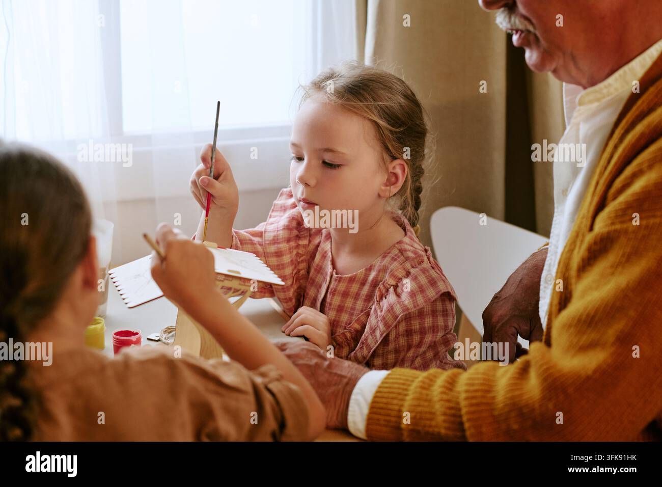 Senior Mann malt Holzhandwerk mit Enkelkindern zu Hause Stockfoto