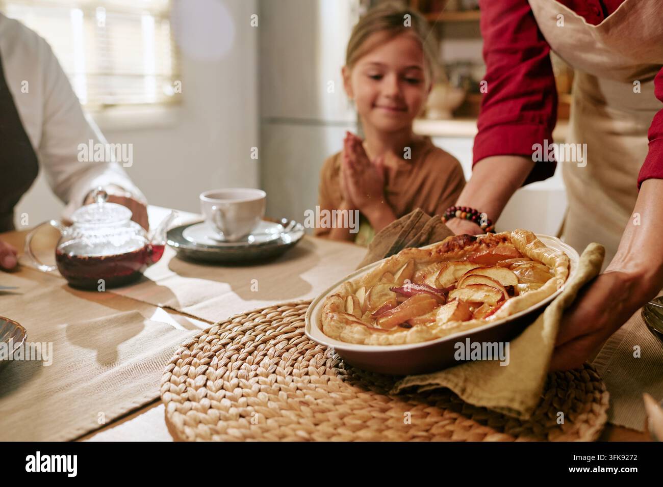 Frau serviert hausgemachten Apfelkuchen an ein glückliches Mädchen beim Familienessen Stockfoto