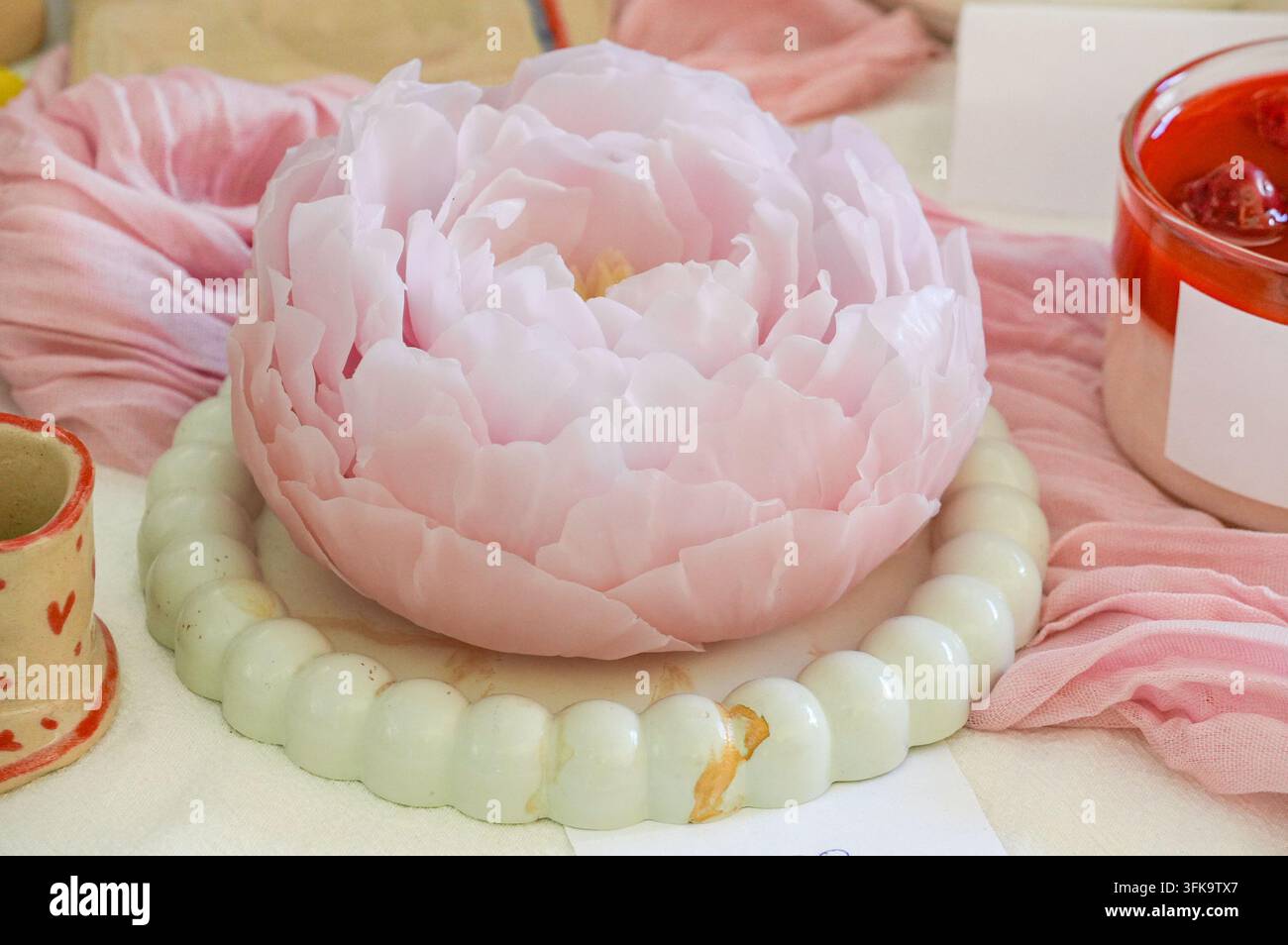 Rosa Pfingstrosenkerzenlicht auf einem Kuchenständer. Stockfoto