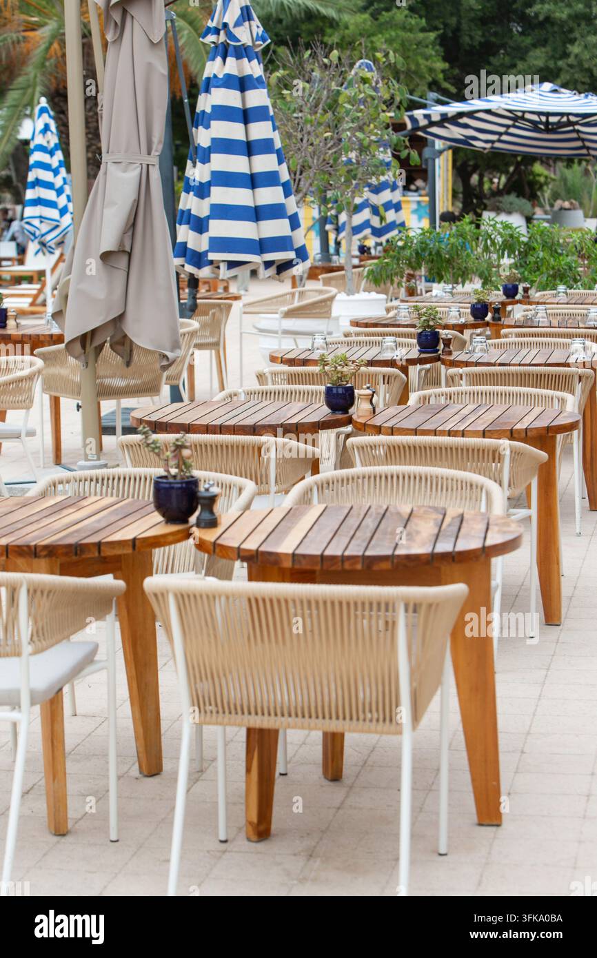 Elegante Außentische und Stühle in einem Luxus-Hotelresort. Stilvoller Außenessbereich in einem modernen Hotelresort mit Holztischen Stockfoto