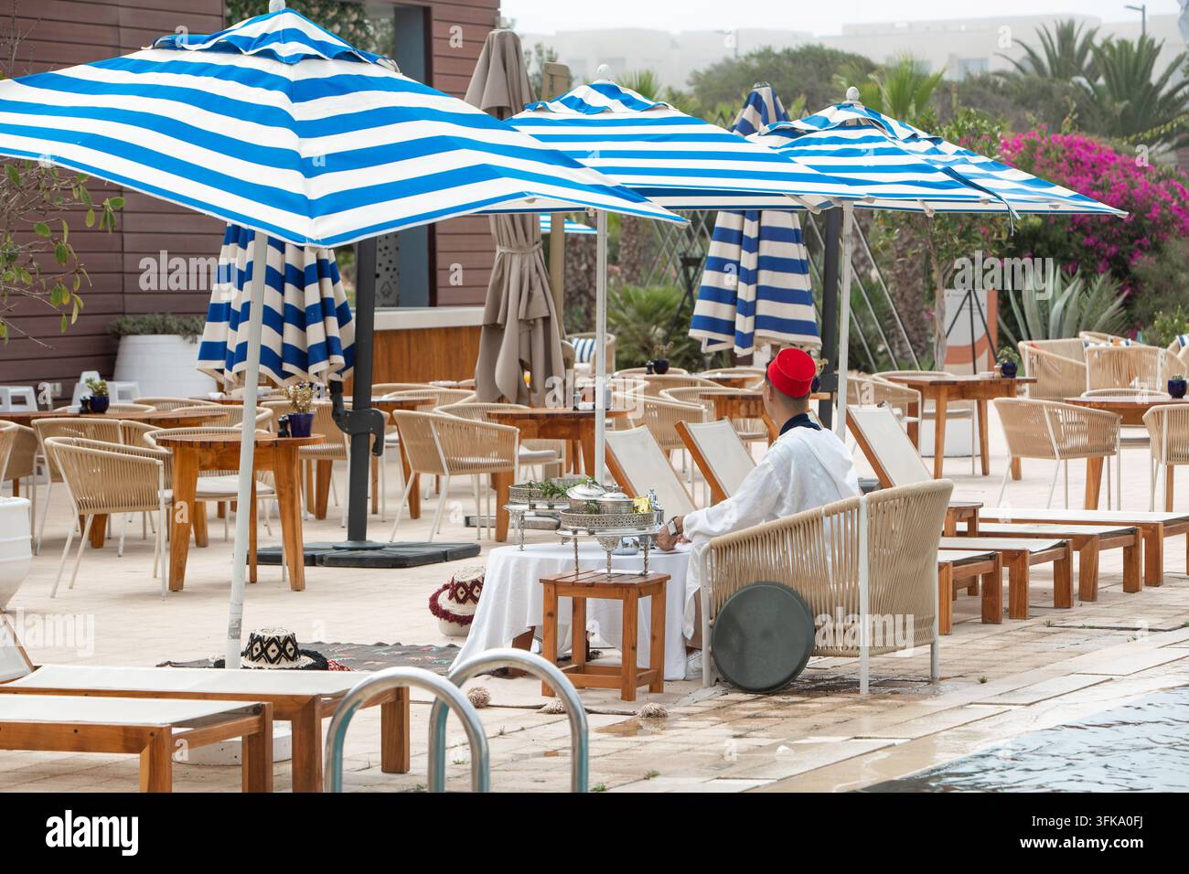 Traditioneller marokkanischer Tee, serviert in einer luxuriösen Poolside-Lounge mit gestreiften Sonnenschirmen. Elegante Poolside-Lounge in einem Luxusresort mit traditi Stockfoto