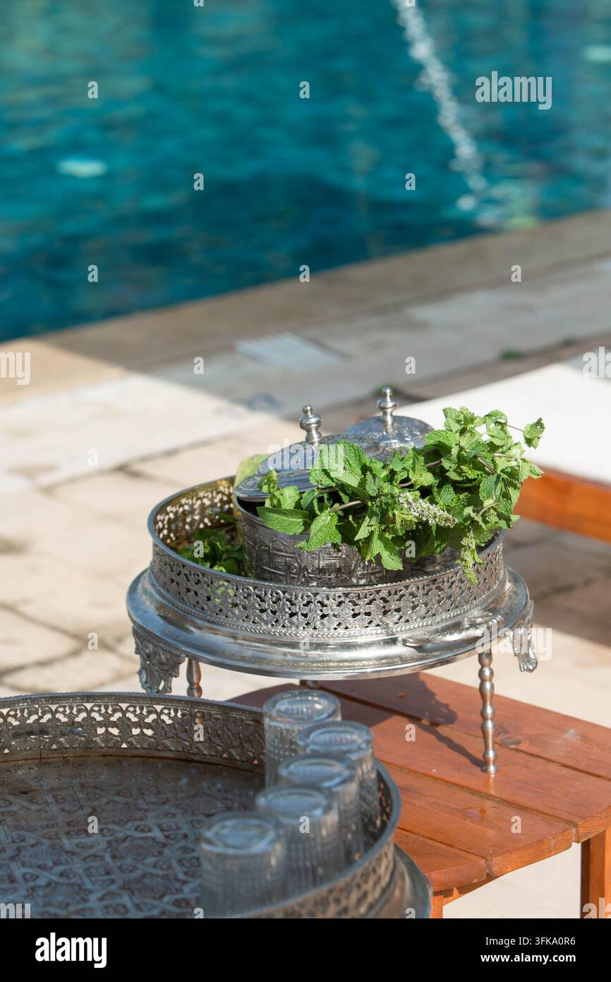 Traditionelles marokkanisches Minztee-Setup neben einem Swimmingpool in einem Luxusresort. Eine traditionelle marokkanische Minztee-Zubereitungsausstattung neben einem Hotel Stockfoto