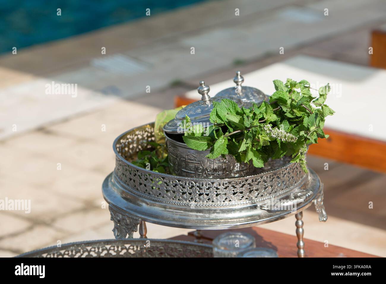 Traditionelles marokkanisches Minztee-Setup neben einem Swimmingpool in einem Luxusresort. Eine traditionelle marokkanische Minztee-Zubereitungsausstattung neben einem Hotel Stockfoto
