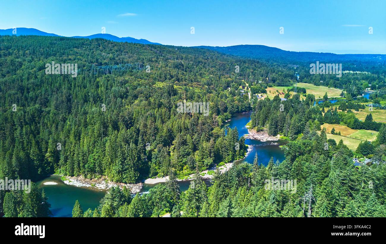 Luftbild zeigt dichte immergrüne Wälder, einen sich windenden Fluss und offene ländliche Lichtungen in Snoqualmie, Washington, an einem klaren Sommertag. Die Szene zeigt Stockfoto
