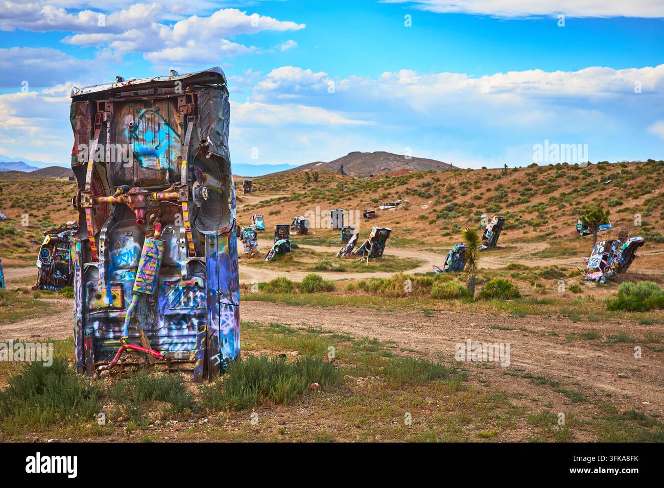 Farbenfroher Graffiti bedeckt verlassene Fahrzeuge, die aufrecht in der trockenen Landschaft von Goldfield Nevada im Internationalen Autowald stehen. Die Szene fängt Stockfoto