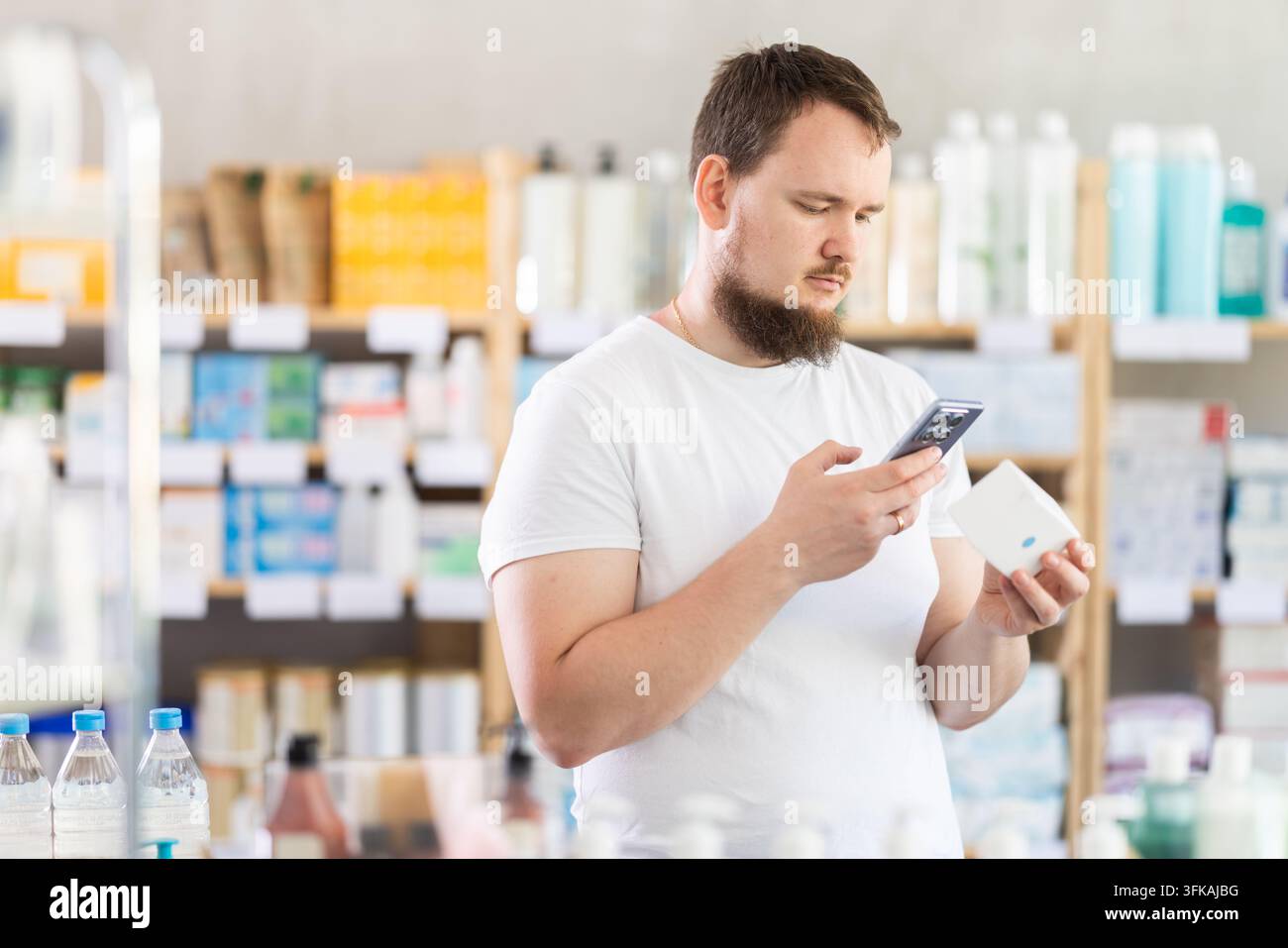 Junger Mann, der den qr-Code von Pillen scannt Stockfoto
