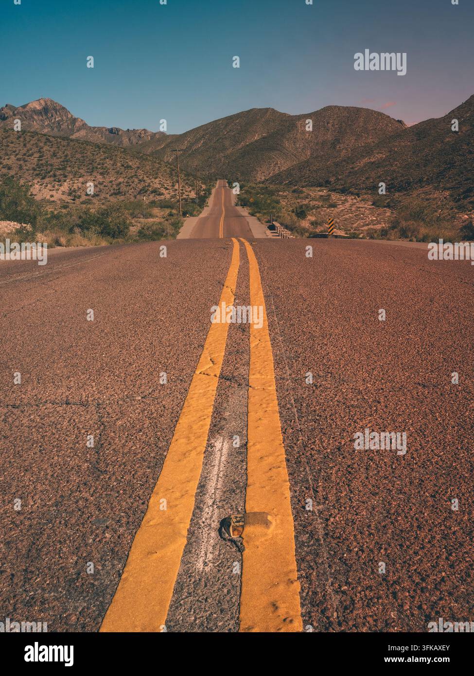 Vertikale Ansicht von doppelten gelben Linien, die auf Wüstenberge in McKelligon Canyon, El Paso, Texas, USA, zuführen. Stockfoto
