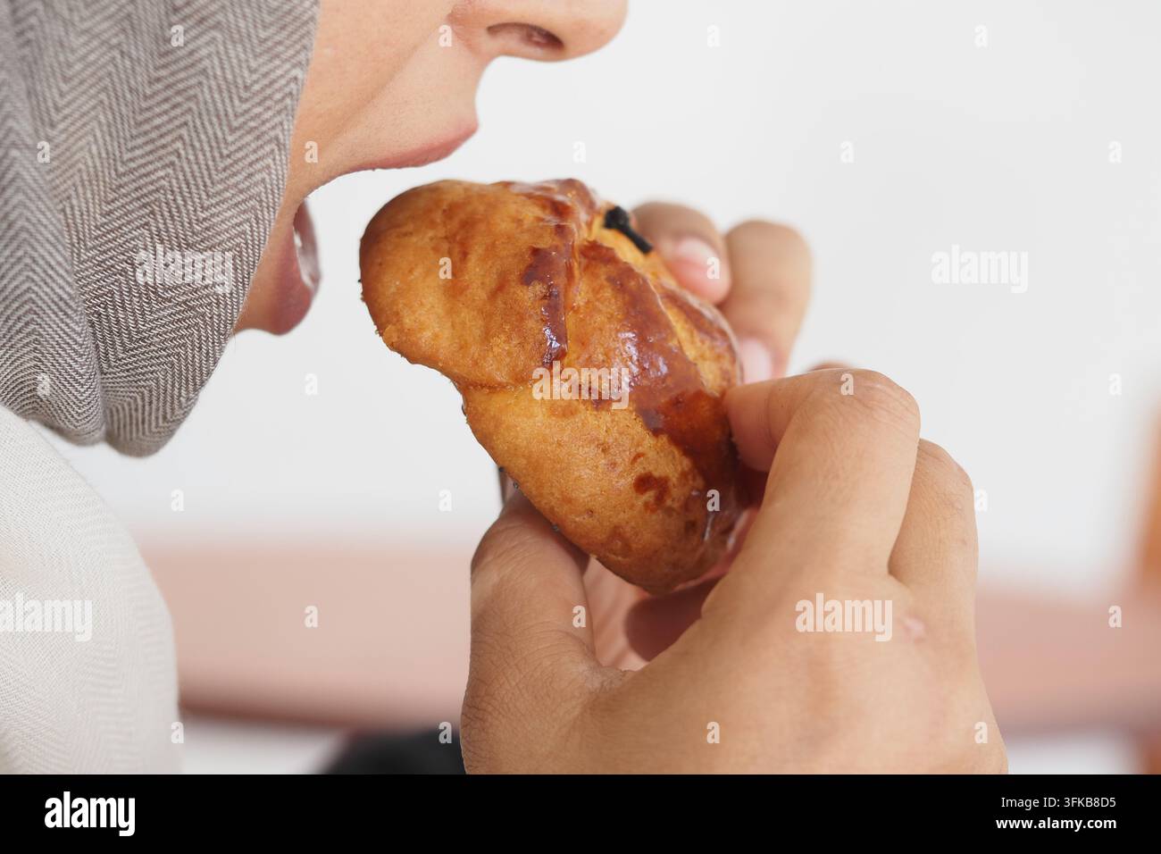 Essen eines süßen Gebäcks in einer lässigen Umgebung, während man einen Snack genießt Stockfoto