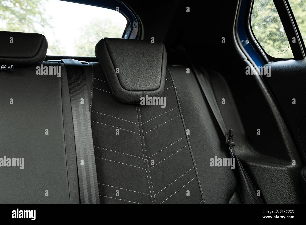 Innenfoto von modernen Auto-Rücksitzen mit dunkelgrauem Stoffbezug, geometrischer Kontrastnaht, integrierten Sicherheitsgurten und Stockfoto