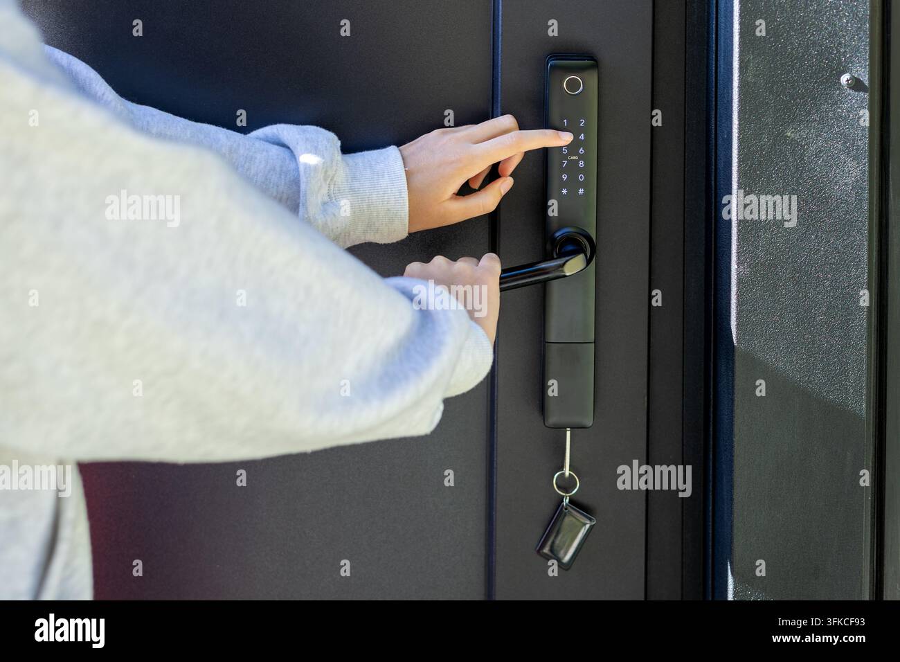 Person, die einen Code auf einem elektronischen Smart-Door-Lock eingibt. Eine Person gibt einen Code auf einem schwarzen elektronischen Tastaturen-Doorschloss ein, während sie den Griff hält, mit einem Stockfoto