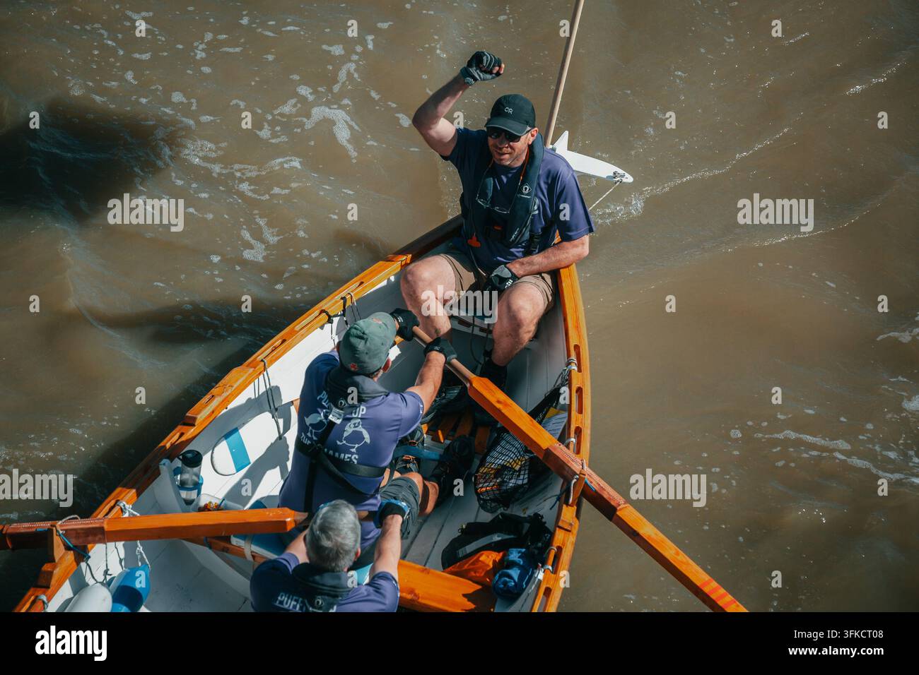 Ein männlicher Steuermann hebt seine Faust in einer Siegesgeste, während er seine Rudercrew während des Great River Race auf der Themse im September 2026 führt Stockfoto