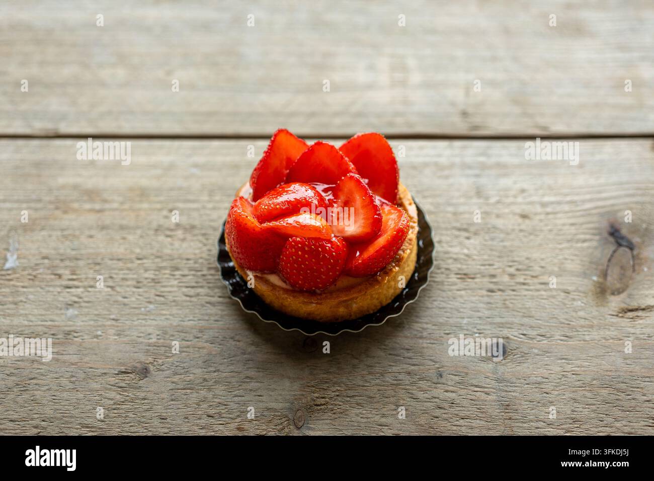 Erdbeertarte mit glasiertem Obst auf rustikalem Holztisch Stockfoto