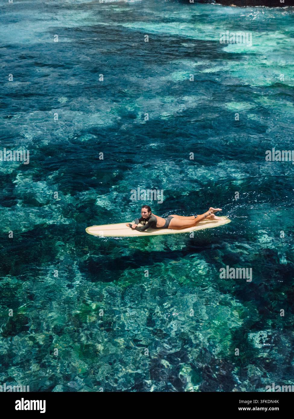 Luftbild einer Surferin, die durch klares türkisfarbenes Wasser gleitet Stockfoto