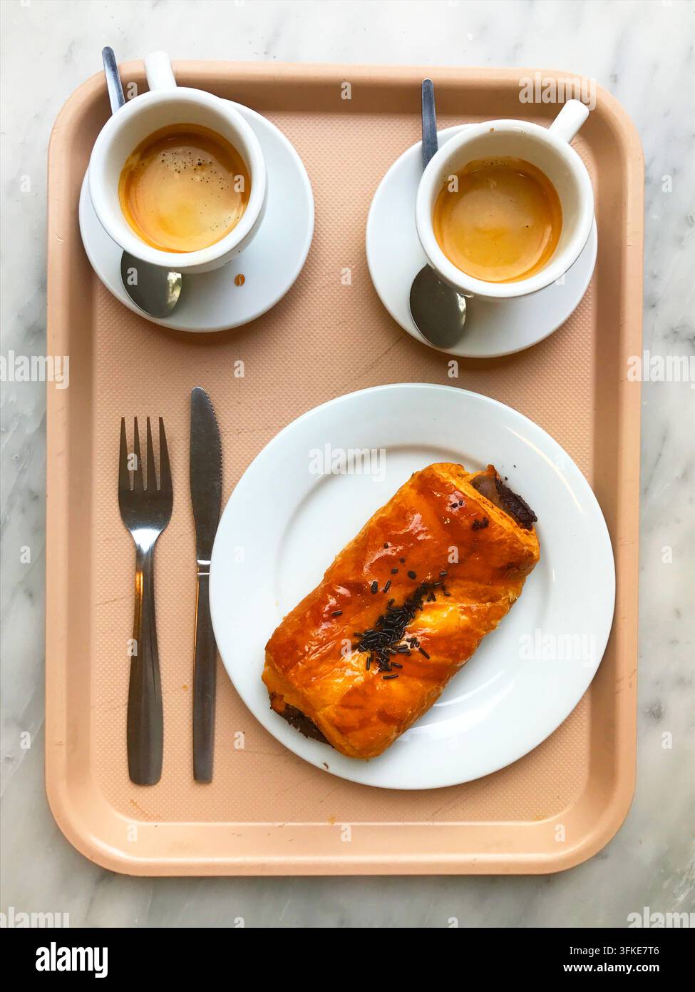Zwei Tassen Kaffee und Schokoladen-Napolitana-Kuchen auf einem Tablett. Blick von oben. Stockfoto