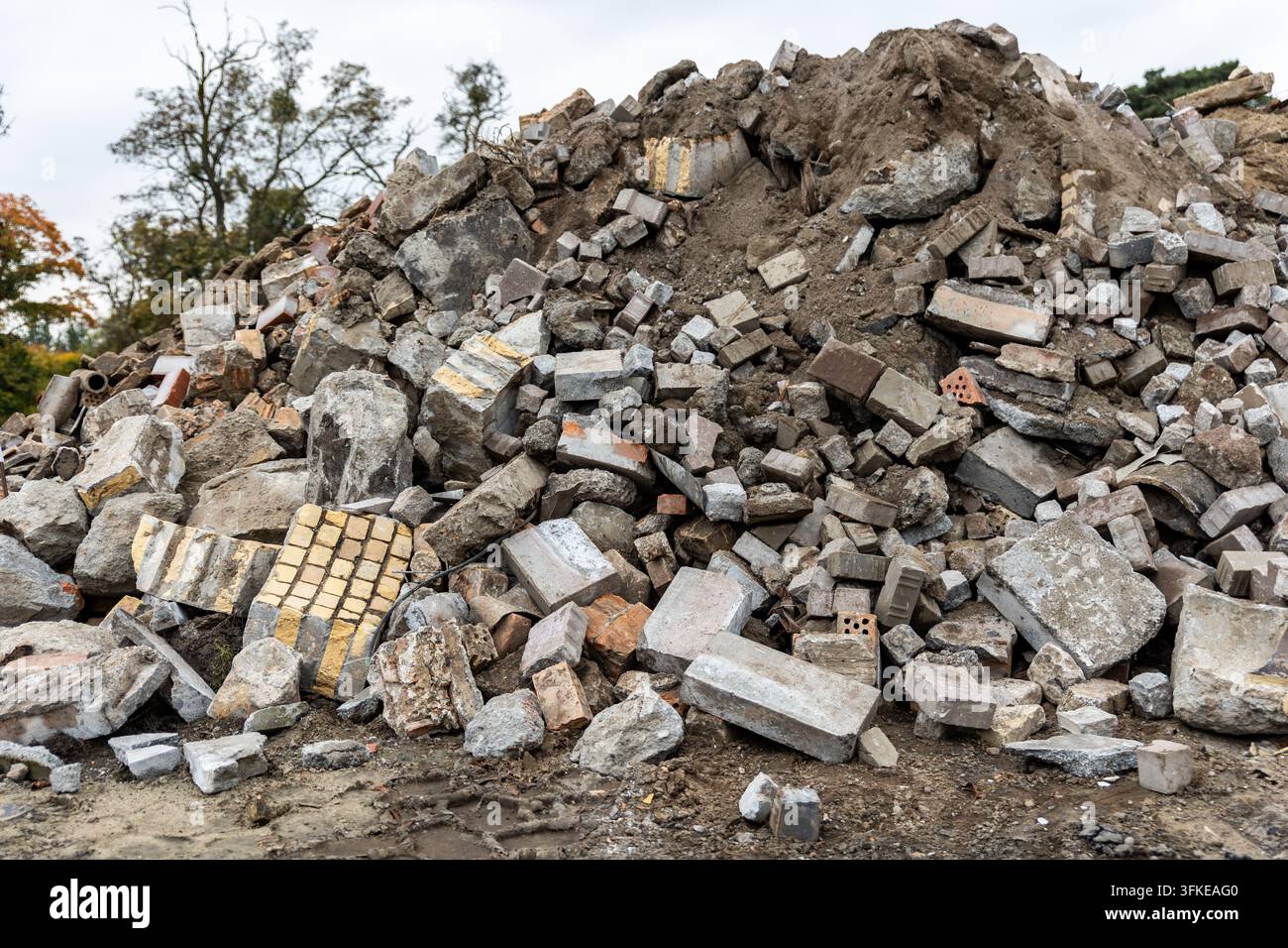 Großer Haufen von Bauschutt enthält zerbrochenen Beton, Ziegelsteine, Pflastersteine und Erde auf der Abbruchstätte. Gemischter Schutt veranschaulicht Baumüll Stockfoto