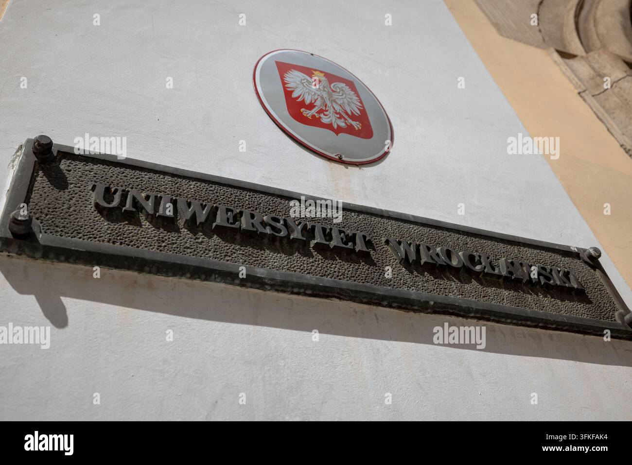 Namensschild der Universität Wrocław und polnisches Weißadler-Emblem, das an einer Außenwand der Universität angebracht ist. Stockfoto