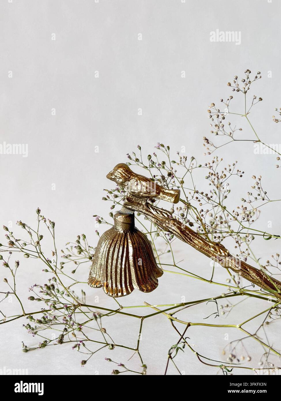 Festliches Goldenes Vogel- und Glockenornament mit zarten Blumenranken und Platz für Text auf hellem neutralem Hintergrund Stockfoto
