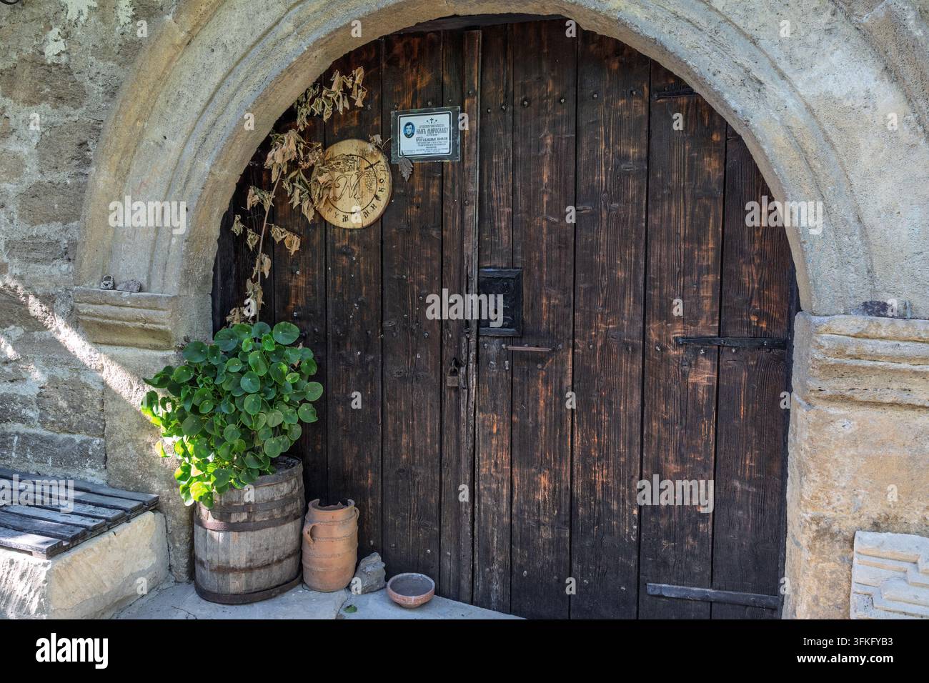 Bogenförmige Holztür der Kellerei mit einer Gedenktafel, Fassblumenerde, Weinhaus Radosavijevic, Dorf Rogijevo, Serbien Stockfoto