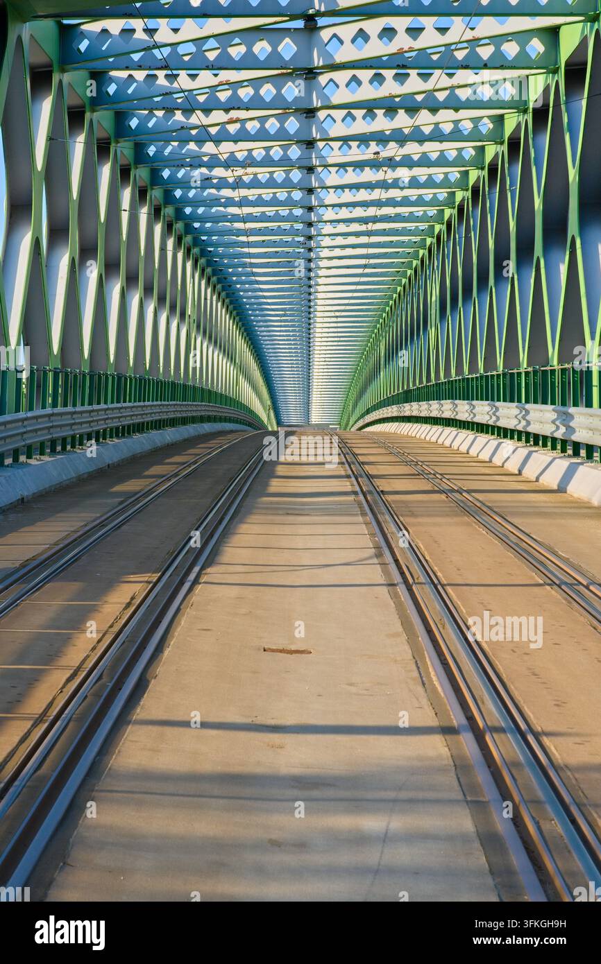 Perspektivansicht einer Stahlträgerbrückenstruktur mit Eisenbahngleisen im Inneren. Stockfoto