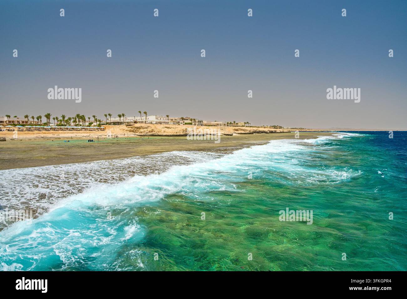 Türkisblaue Meereswellen brechen am sandigen Strandufer in Marsa Alam, Ägypten Stockfoto