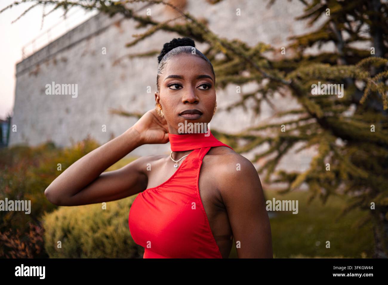 Elegante Frau in einem auffälligen roten Kleid posiert anmutig vor einem wunderschönen natürlichen Hintergrund Stockfoto