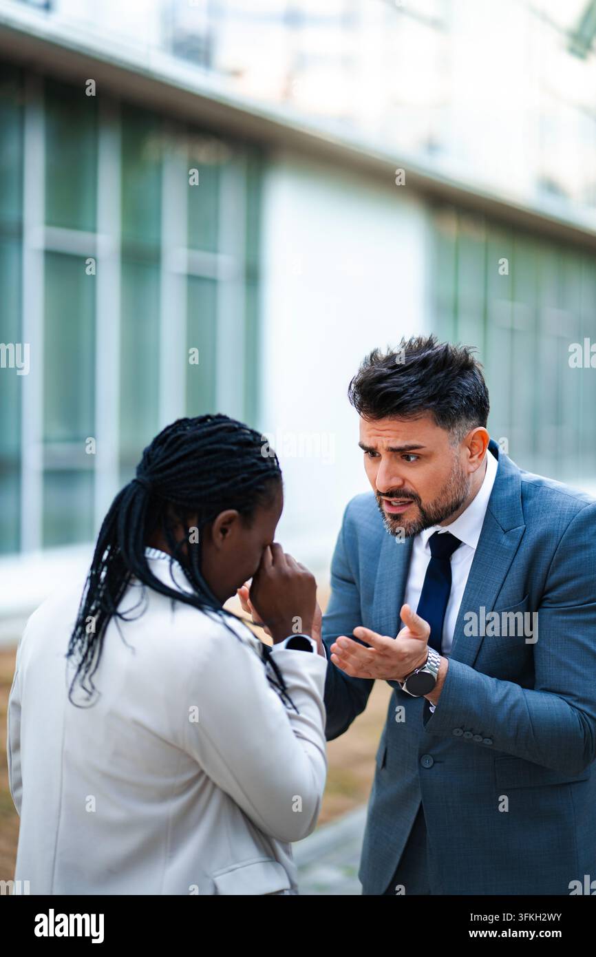 Wütender Chef schreit einen weinenden Angestellten an, der Arbeitsplatzmissbrauch erlebt Stockfoto