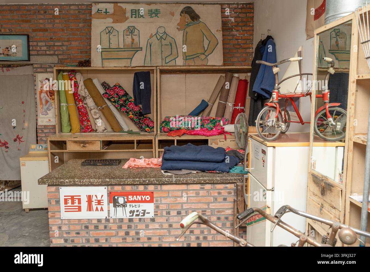 Vintage-Schneiderei-Interieur, Regale mit bunt gemustertem Stoff und altem Eiscremeschild Stockfoto