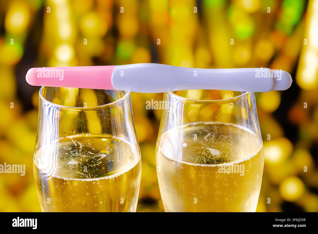 Schwangerschaftstest, der auf Champagnergläsern ruht, die das neue Jahr feiern Stockfoto