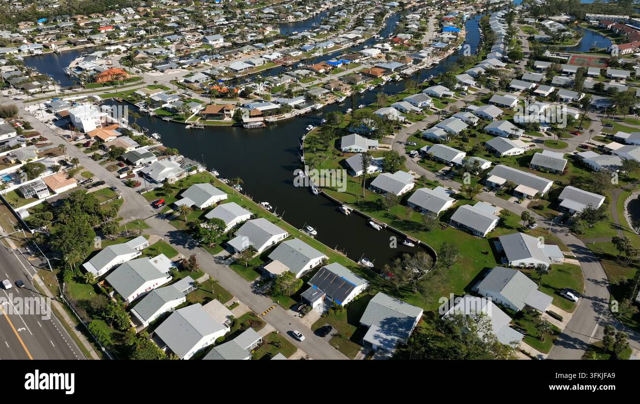 Weiße Luxus Häuser mit grauem Dach und privatem Flusszugangsteg in Bradenton, Florida. Sonniger Tag mit geparkten Booten am Steg. Sommertag in nob Stockfoto