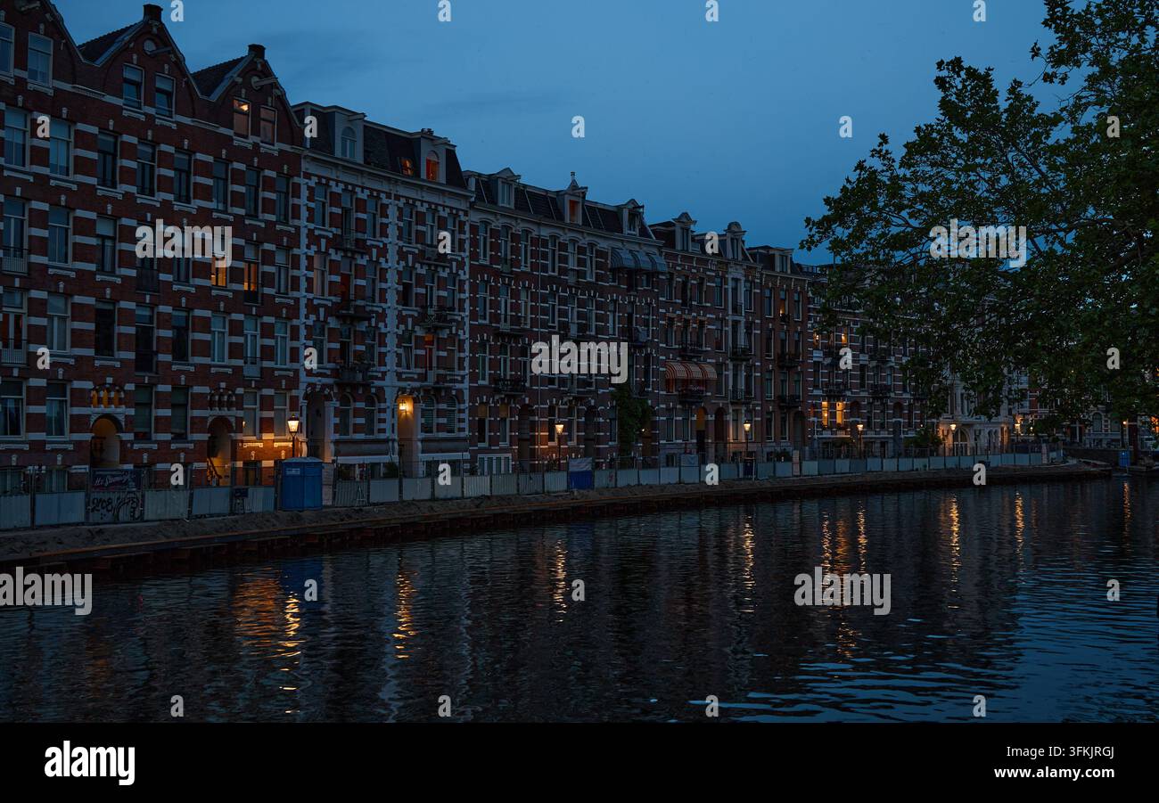 Historische Kanalhäuser, die sich bei Dämmerung in Amsterdam spiegeln Stockfoto