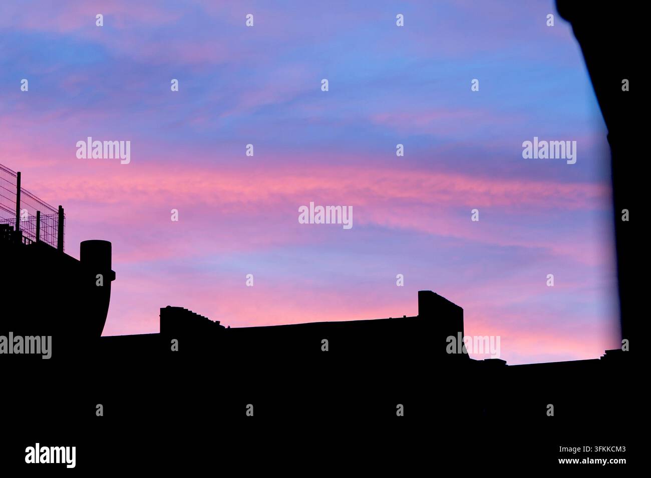 Heller rosa Sonnenuntergang mit Gebäudesilhouetten Stockfoto