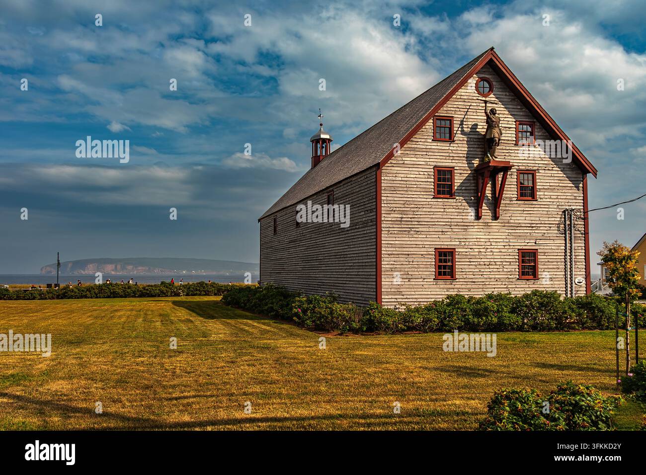 Historisches Bell House, eine verwitterte Holzscheune mit rotem Zierrand und einer Statue auf dem Giebel, nahe der Bucht von Perce. Perce, Gaspesie, Quebec, Kanada, Nordamerika Stockfoto