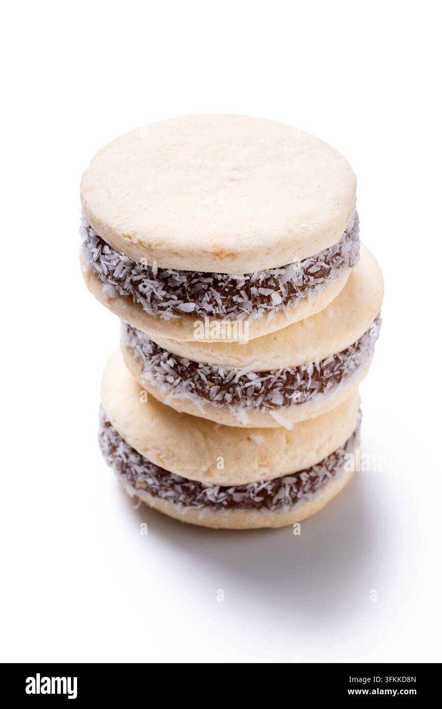 Stapel traditioneller Alfajores aus weichen Keksen, gefüllt mit Dulce de Leche und mit Kokosraspeln überzogen, isoliert auf weißem Hintergrund. Stockfoto
