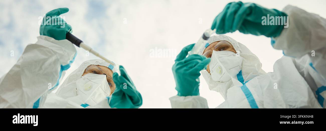 Kopfzeile von Wissenschaftlern in Schutzanzügen, die medizinische Forschung im Freien durchführen Stockfoto