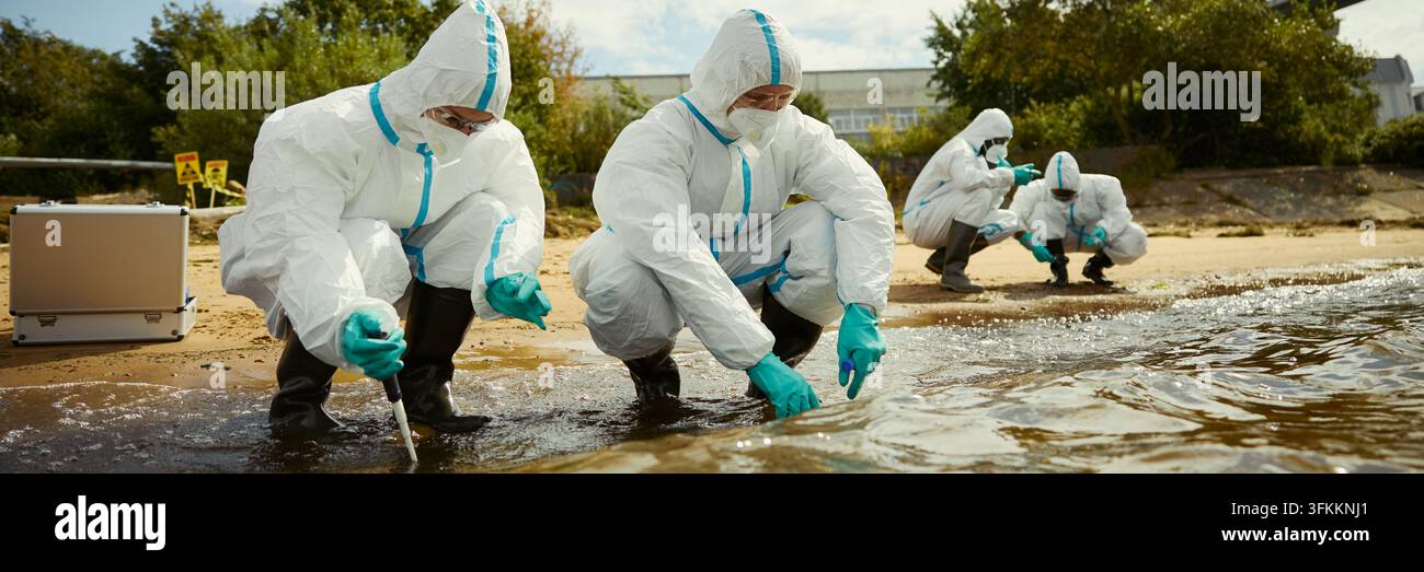 Kopfzeile von Diversen Wissenschaftlern in Schutzanzügen, die im Freien Wasserproben nehmen Stockfoto