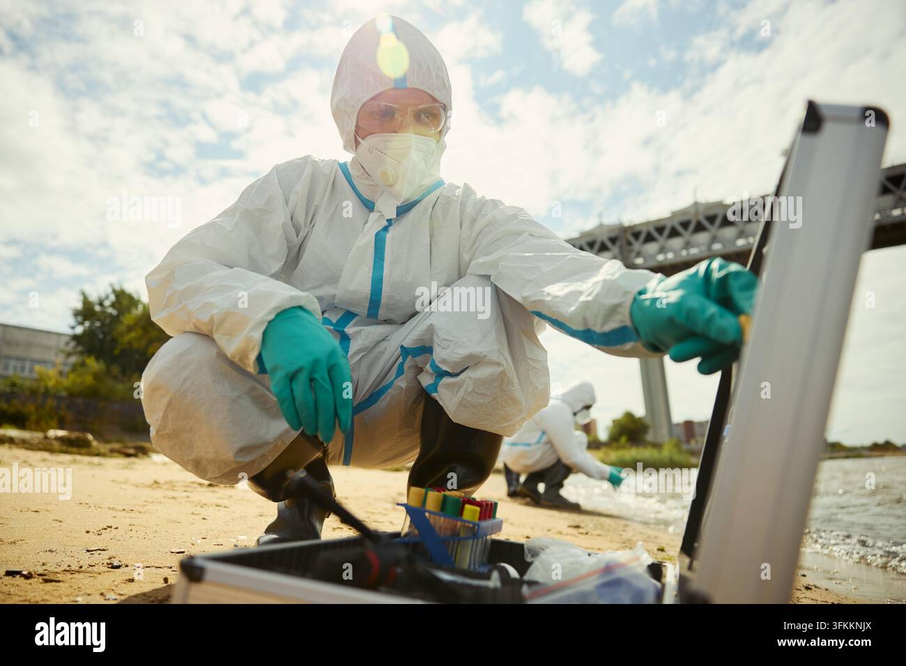 Porträt eines Wissenschaftlers in Schutzanzug, der Wasserproben nimmt Stockfoto