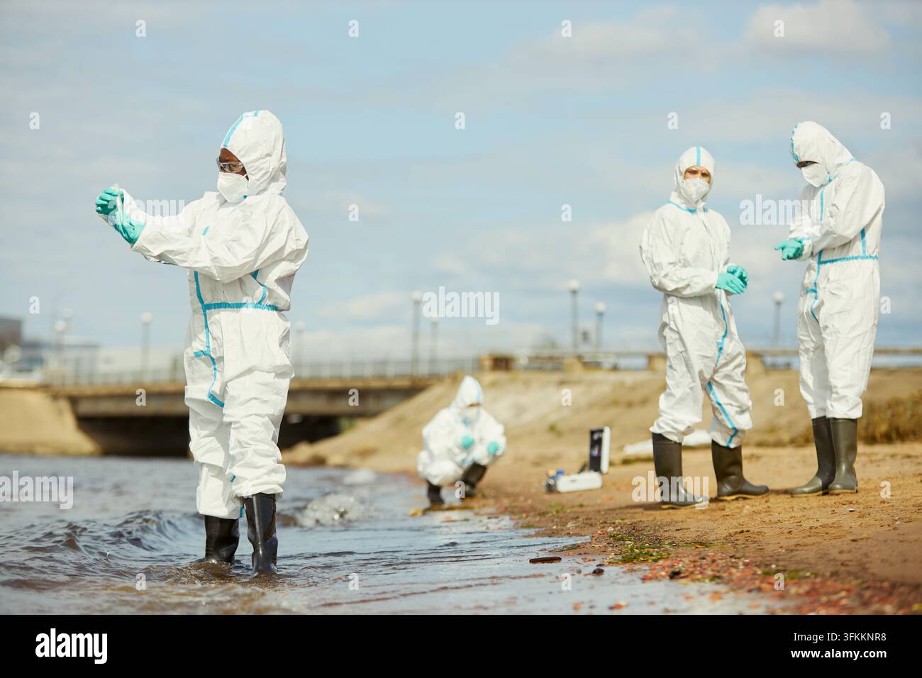 Ökologisches Forschungsteam in Schutzanzügen testet Küstenwasser Stockfoto