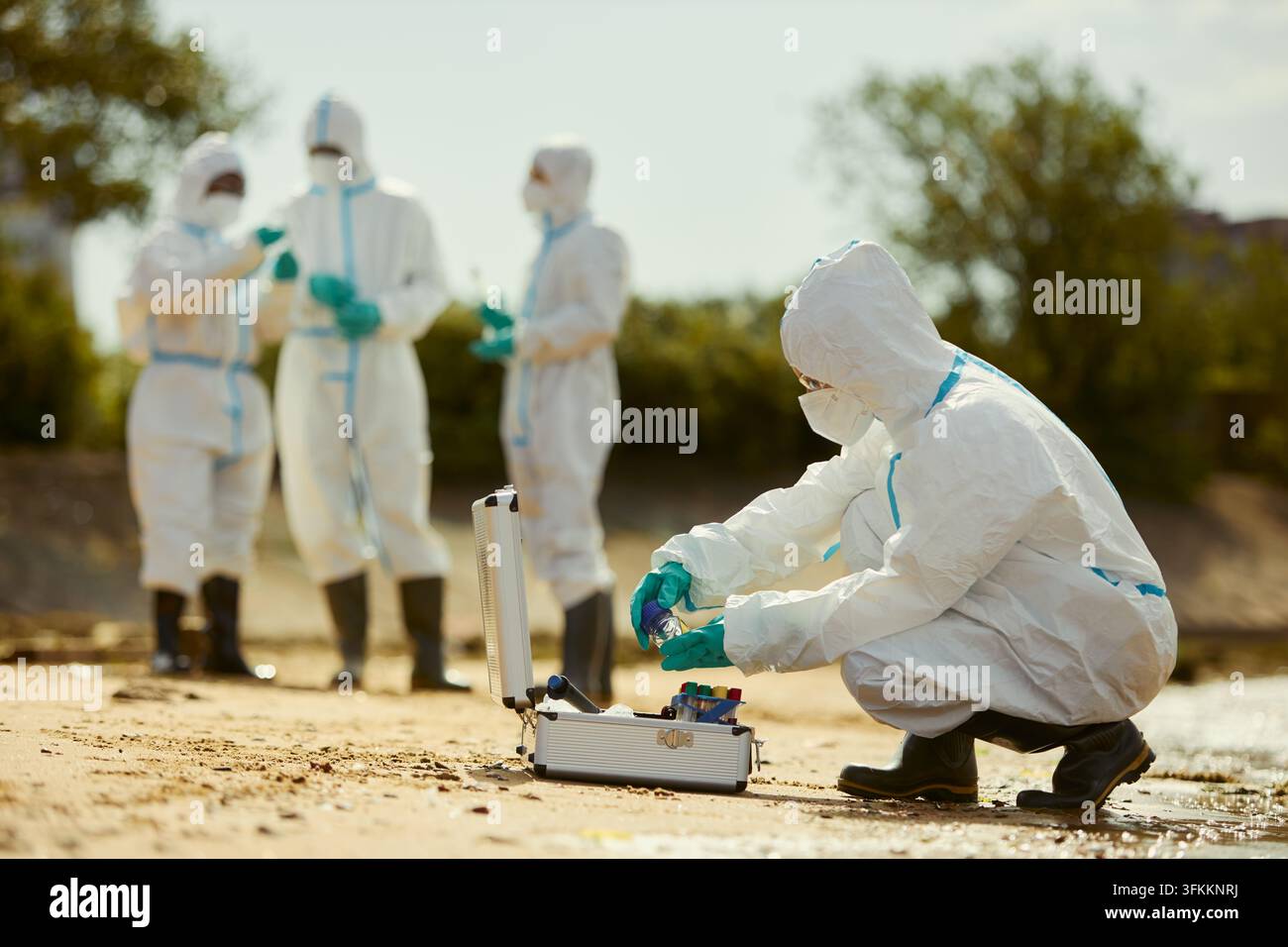 Ökologe in Chemikalienschutzanzug, der Wasserproben im Freien sammelt Stockfoto
