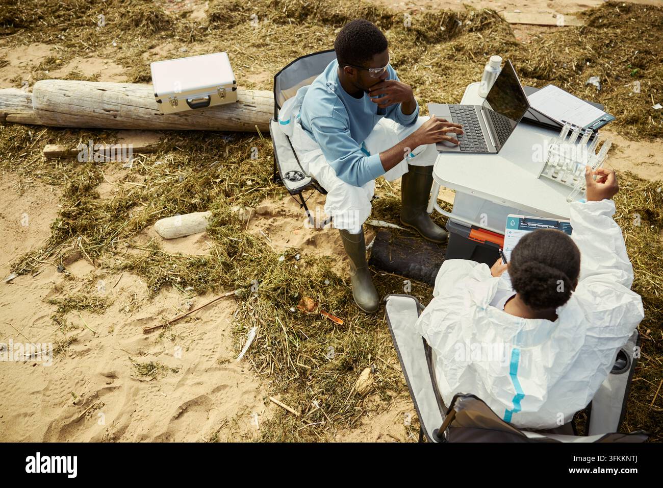 Schwarze Wissenschaftler analysieren ökologische Wasserproben im Freien am Laptop Stockfoto