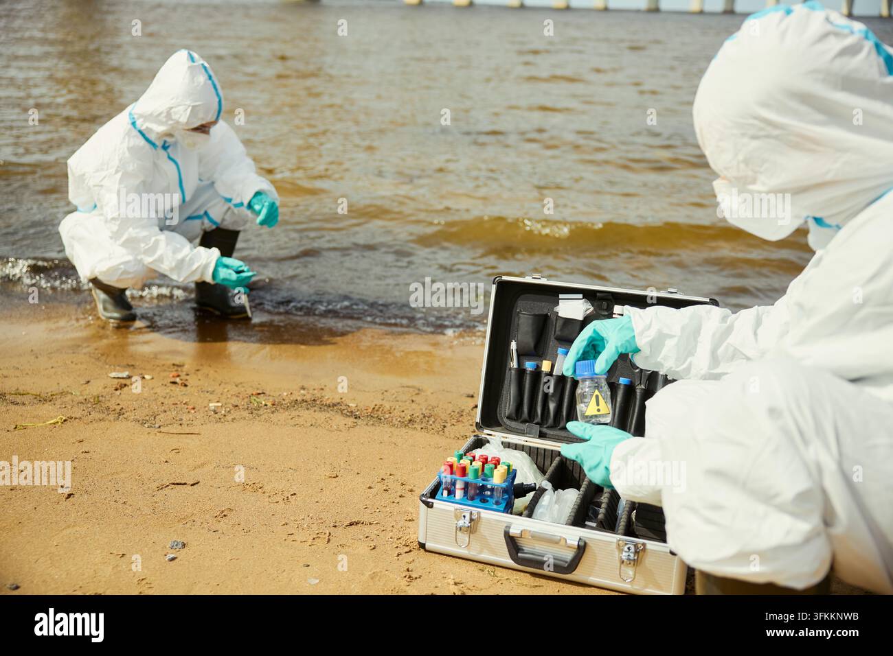 Ökologen in Schutzanzügen testen die Wasserqualität im Freien Stockfoto