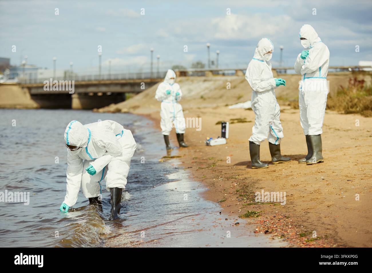 Ökologen in Hazmat-Anzügen, die Wasserproben für einen Verschmutzungstest sammeln Stockfoto