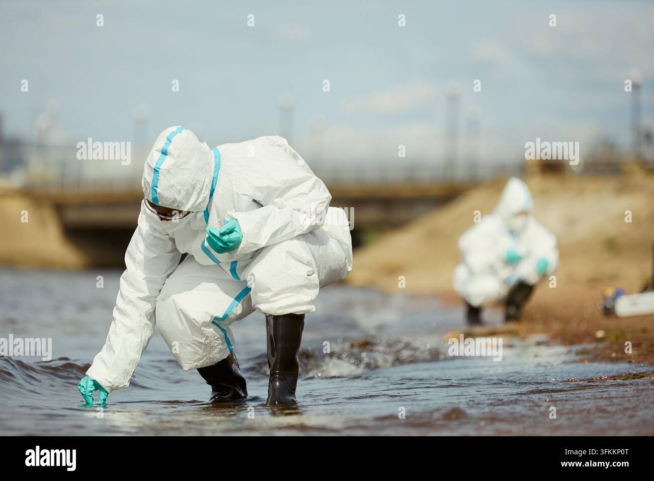 Ökologen in Schutzanzügen, die im Freien Wasserproben sammeln Stockfoto
