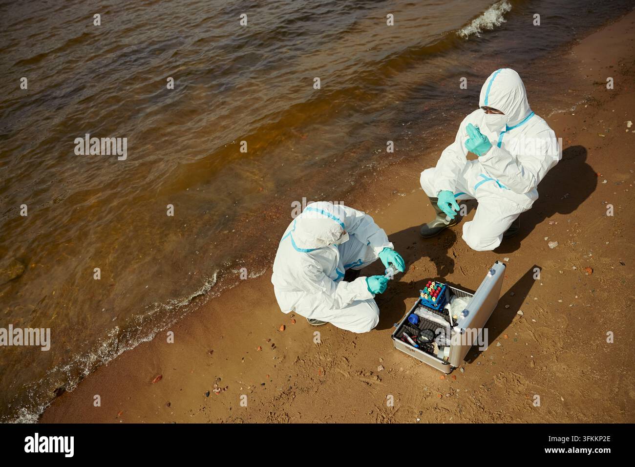 Ökologen in Schutzanzügen testen die Wasserqualität an der Küste Stockfoto