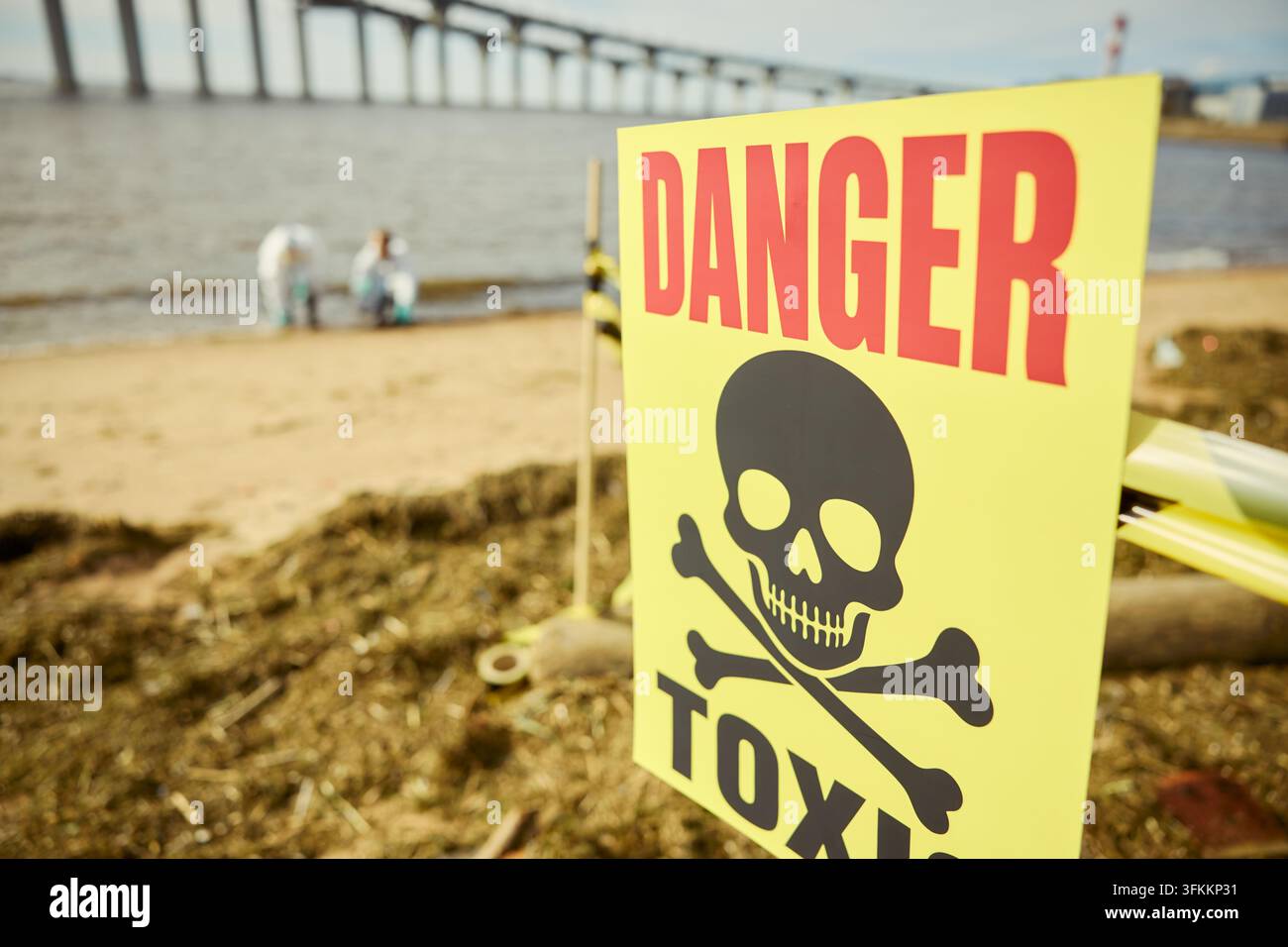 Gift-Warnschild auf verschmutzter Strandfläche mit Wissenschaftlern Stockfoto
