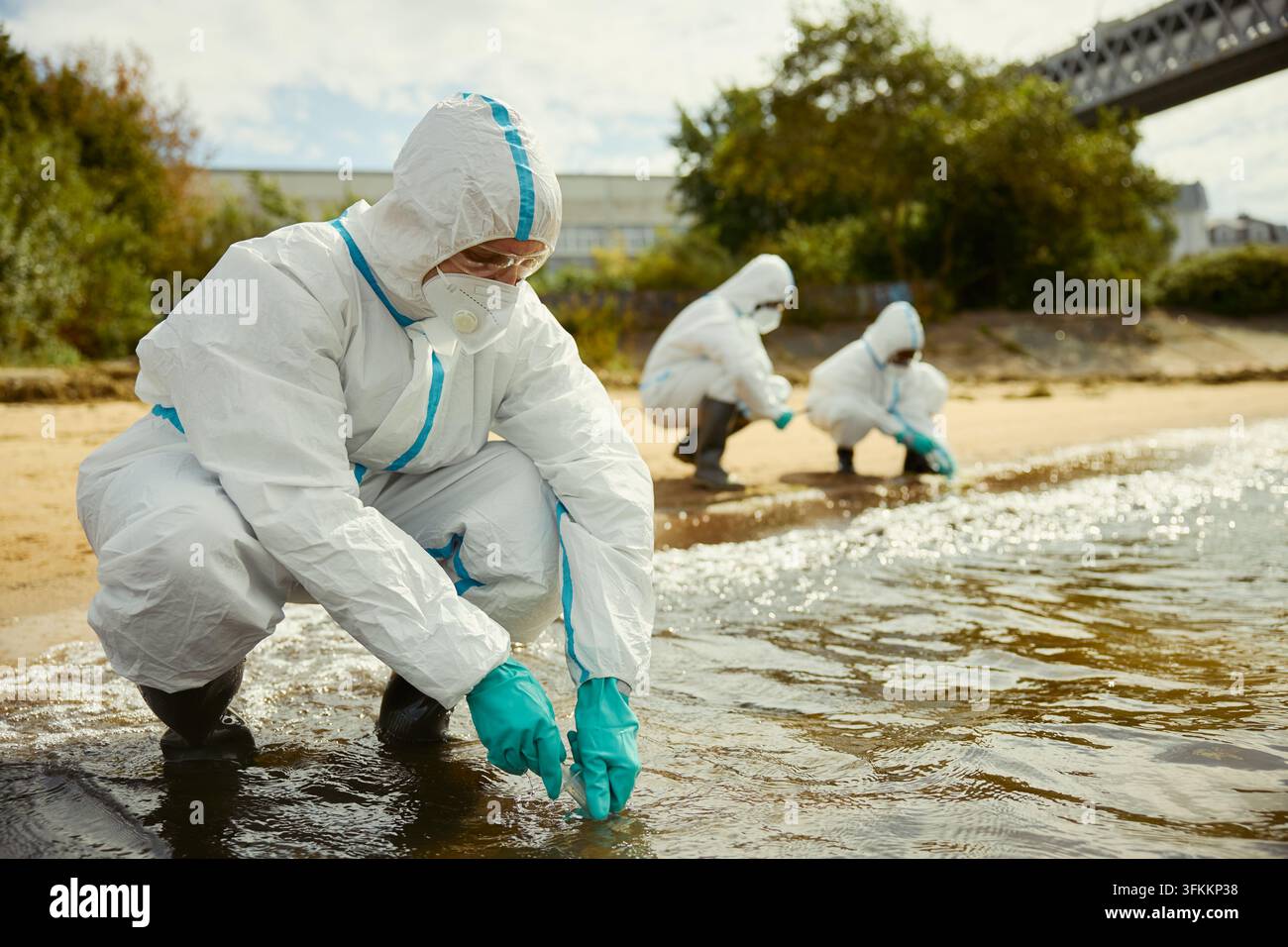 Wissenschaftler in Schutzanzügen, die im Freien Wasserproben sammeln Stockfoto
