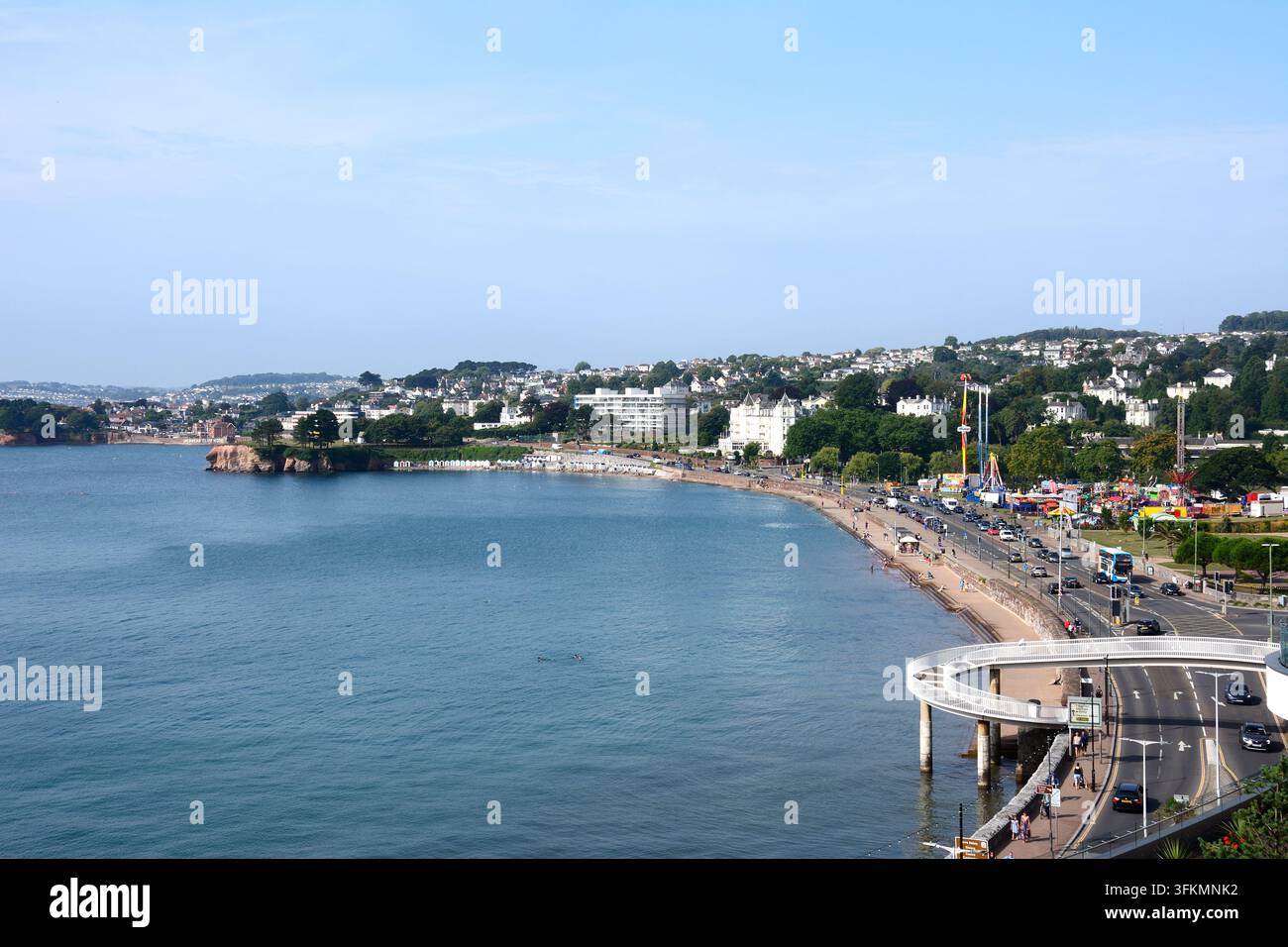 Erhöhte Ansicht entlang des Strandes und der Küste mit der Fußgängerbrücke im Vordergrund und den Stadtgebäuden im Hintergrund, Torquay, UK. Stockfoto